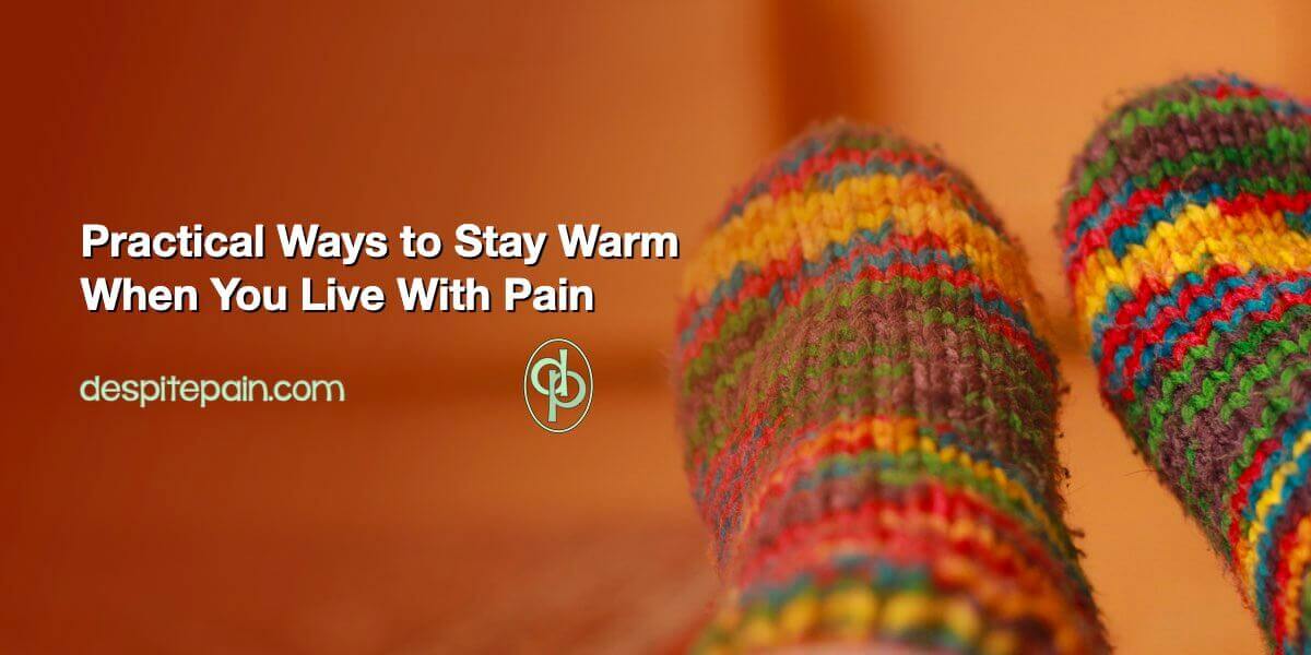 Practical ways to stay warm when you live with pain is written in white text against a warm peach coloured background. At the right side of the pic, there is a colourful pair of socks on someone's feet.
