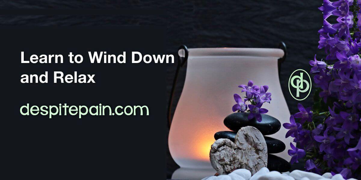 Text: learn to wind down and relax. The picture has a black background. There is a small light at the right hand side, with a pile of black pebbles and purple flowers